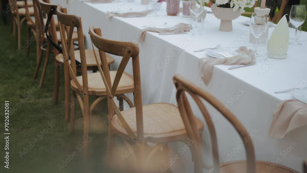 Wedding decoration, old fashioned chairs near the festive table setting with pastel silk napkins, small wedding party, slow motion. Wedding decoration, old fashioned chairs near the festive table setting with pastel silk napkins, small wedding party, slow motion.