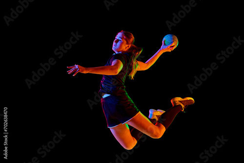 Принти на полотні Fit, young, competitive female handball player demonstrating throwing techniques against black background in neon light