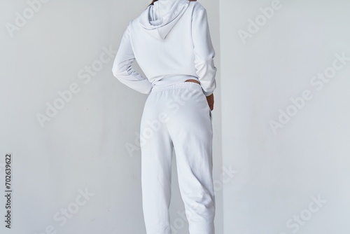 Back view of a young woman wearing white minimalist sweatpants. Step into Comfort with a Chic White Outfit Perfect for Casual Elegance. Sportwear mock-up. Girl in white pants.