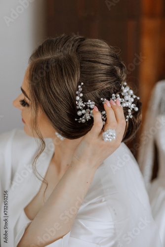 Luxurious wedding barrette on the head of the bride's hairstyle. The morning of the wedding preparation of the bride who touches the hairpin on her head with her hand.