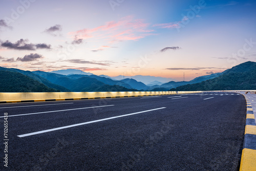 Asphalt highway road and green mountains with sky clouds at dusk