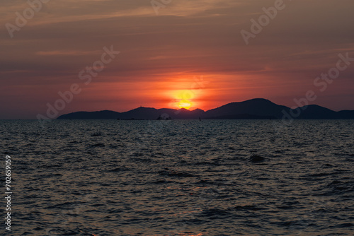 Beautiful golden sunset over the sea behind mountains in background and have light reflection on the water as the sunset.