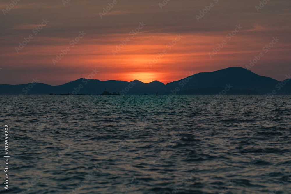 Beautiful golden sunset over the sea behind mountains in background and have light reflection on the water as the sunset.