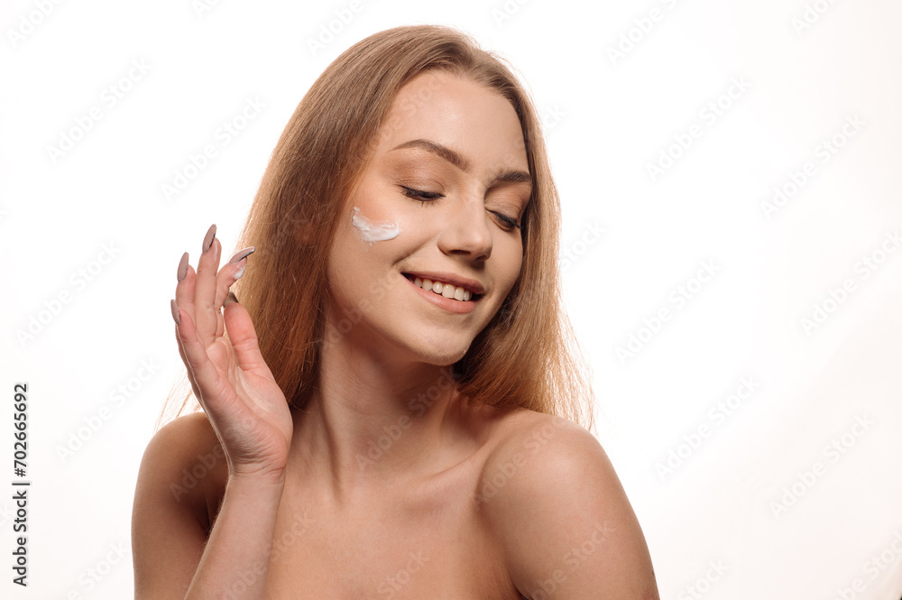 Beauty portrait of a beautiful girl or woman applying cream on her face on an isolated white background Beauty portrait of a beautiful girl or woman applying cream on her face on an isolated white background