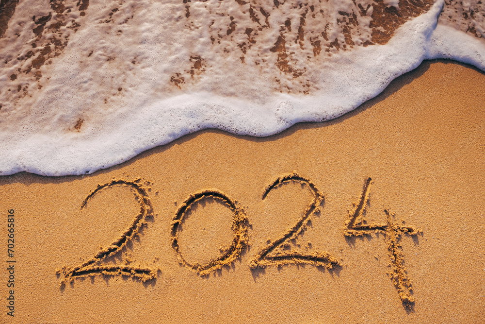 Fototapeta premium Happy New Year 2024 Text on Tropical Beach Sand, Caribbean sea sunrise and waves on the shore.