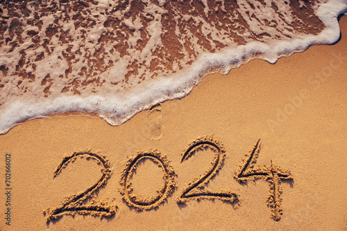 Happy New Year 2024 concept, lettering on the beach sand