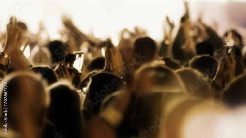 Crowded people in a night party concert view. Young celebrating guys dancing and clapping hands in joyfull concert taking photos and videos for social media sharing.  photo