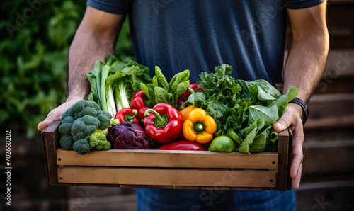 A man holding a box with fresh vegetables. Healthy eating concept.