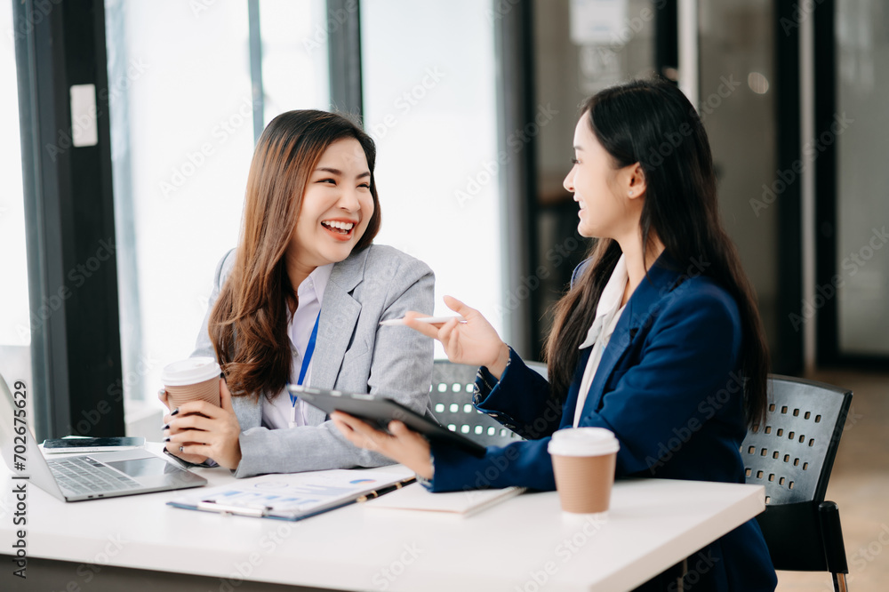 Two Asian businesswoman discuss investment project working and planning strategy with tablet laptop computer Two Asian businesswoman discuss investment project working and planning strategy with tablet laptop computer