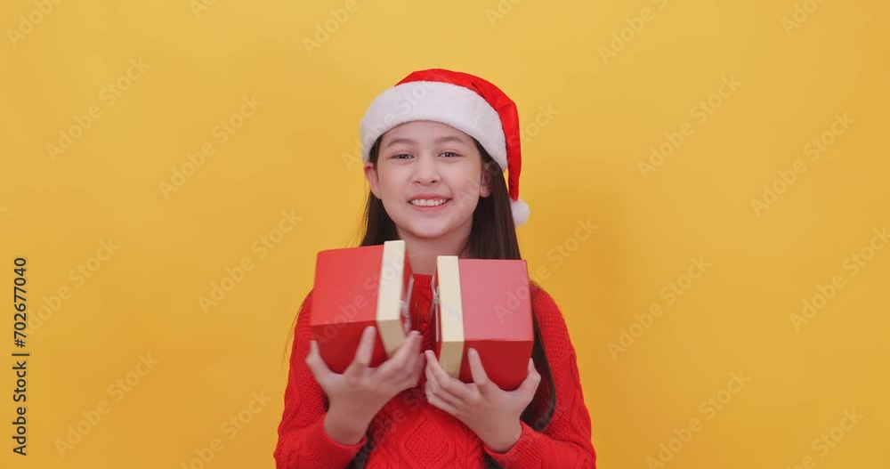 Cute little girl wearing a Christmas costume holding gift boxes. Isolated on yellow background in studio. Cute little girl wearing a Christmas costume holding gift boxes. Isolated on yellow background in studio.
