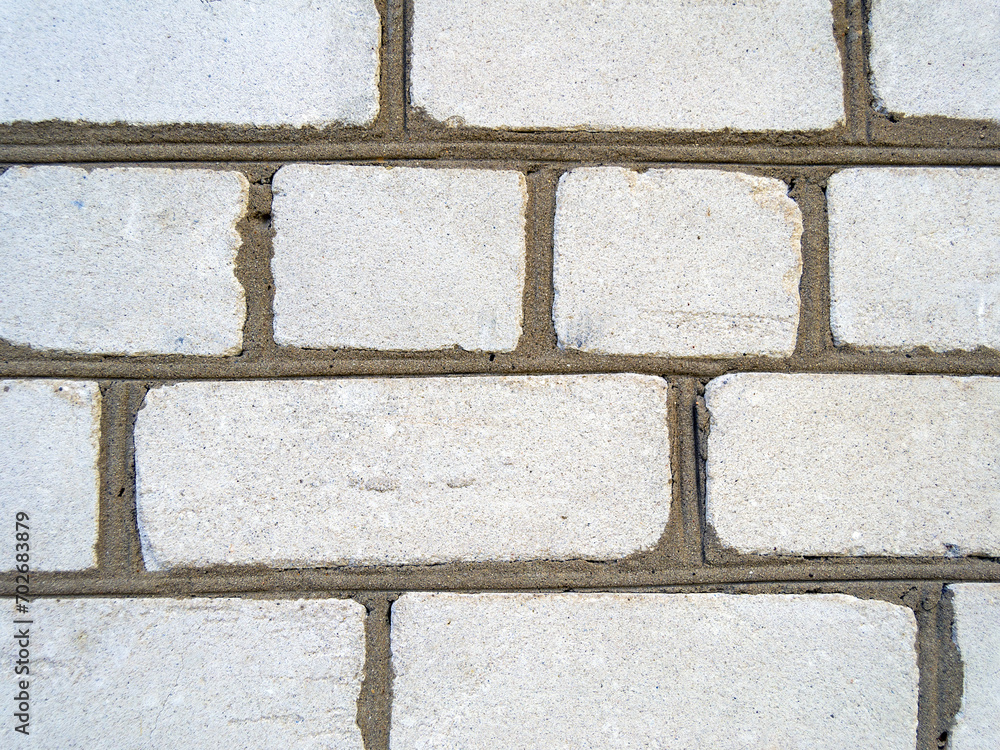 Fototapeta premium An image of the texture of a brick wall with a coarse-grained, embossed surface. Small cracks and cement inclusions. Horizontal image.