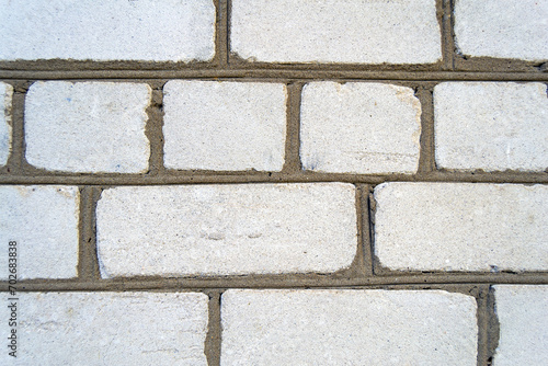 An image of the texture of a brick wall with a coarse-grained, embossed surface. Small cracks and cement inclusions. Horizontal image.