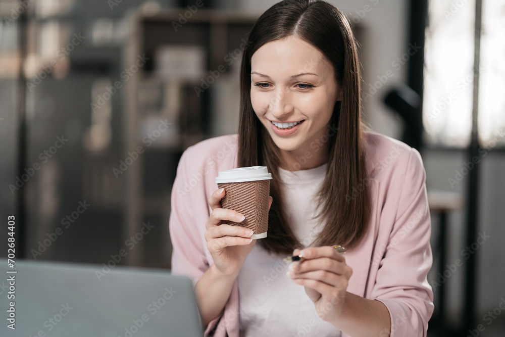 businesswoman sits in a office working on laptop and enjoys a coffee. businesswoman sits in a office working on laptop and enjoys a coffee.