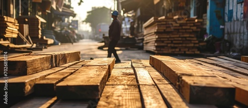 A worker unloads wooden boards on the street, storing building materials in a warehouse. © 2rogan