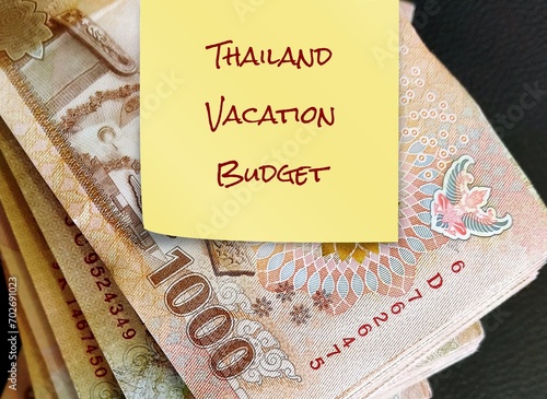 Thai Bath banknotes cash money with yellow stick note written THAILAND VACATION BUDGET, concept of traveller financial plan for a trip to Thailand, popular dream destination photo