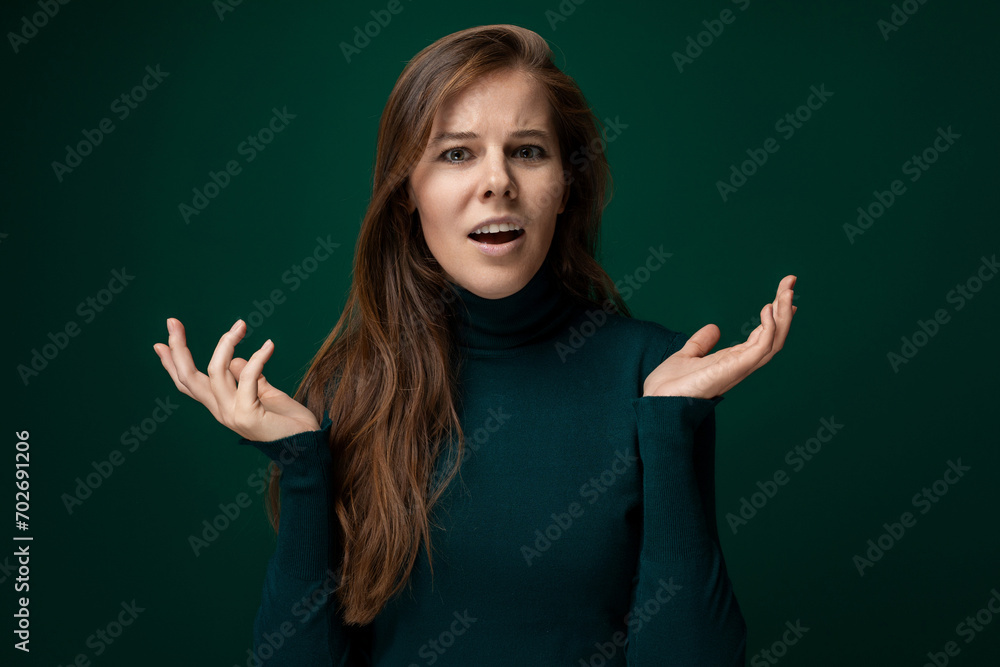 Young pretty woman with long brown hair waving her arms on a green background with copy space Young pretty woman with long brown hair waving her arms on a green background with copy space