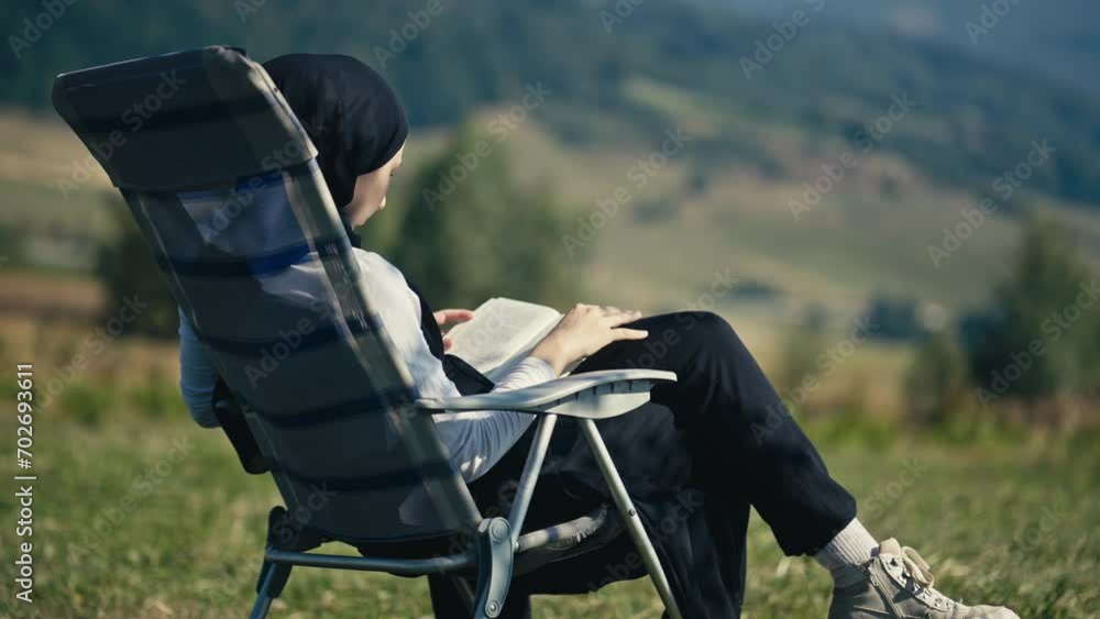 Teenage Muslim Girl Turning Pages of a Book on a Picnic Chair in Nature Teenage Muslim Girl Turning Pages of a Book on a Picnic Chair in Nature