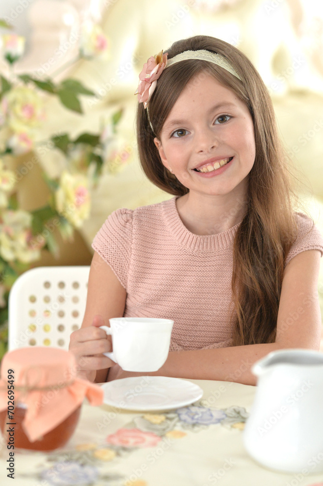 Smiling girl drinking tea at the table