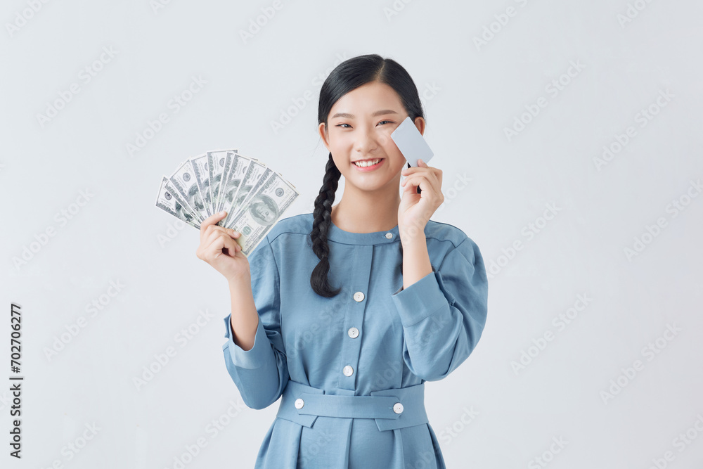 Young pretty asian woman wearing glasses shows a bank card and a fan of dollar bills Young pretty asian woman wearing glasses shows a bank card and a fan of dollar bills