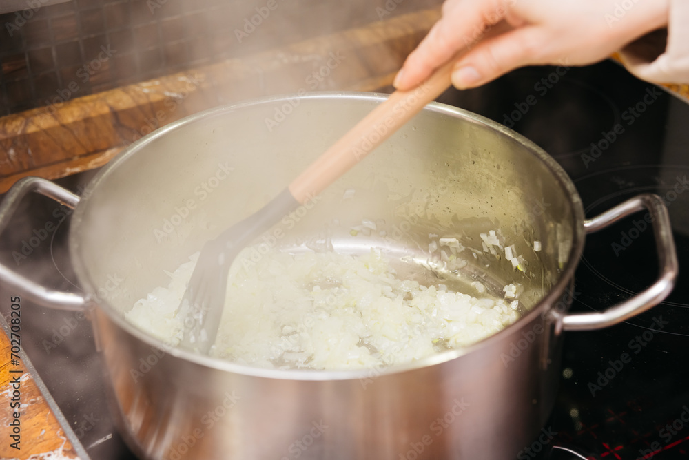Sauteing Onions in a Stainless Steel Saucepan. A chef sautes diced onions in a stainless steel saucepan over a stove, the beginning steps of a flavorful meal preparation. Sauteing Onions in a Stainless Steel Saucepan. A chef sautes diced onions in a stainless steel saucepan over a stove, the beginning steps of a flavorful meal preparation.