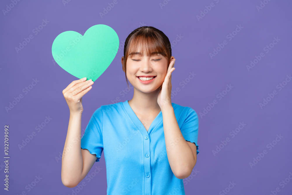 Portrait of cheerful person hold heart postcard toothy smile isolated on violet color background Portrait of cheerful person hold heart postcard toothy smile isolated on violet color background