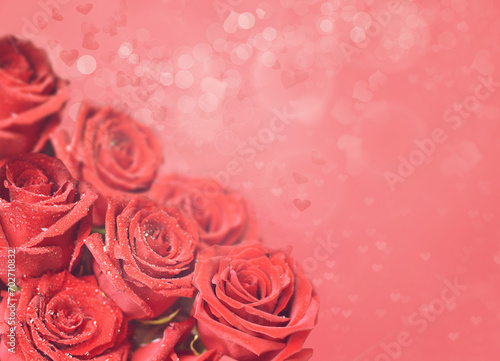 A bouquet of bright scarlet roses on a pink soft background with heart-shaped bokeh