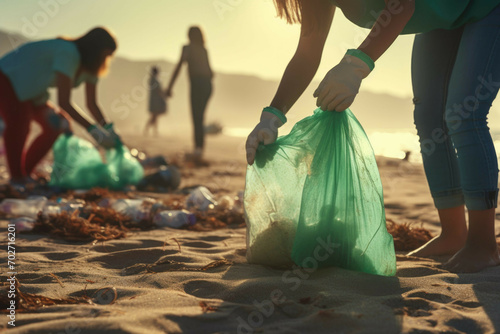 men and women in green top gloves collect garbage on sandy beach photo
