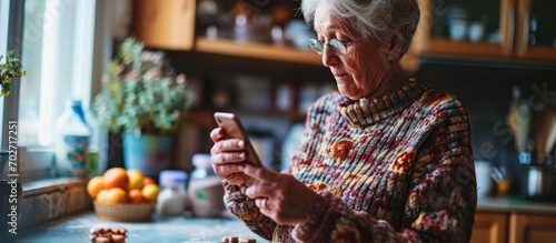 Senior woman uses smartphone to check recipe while holding a pill. photo