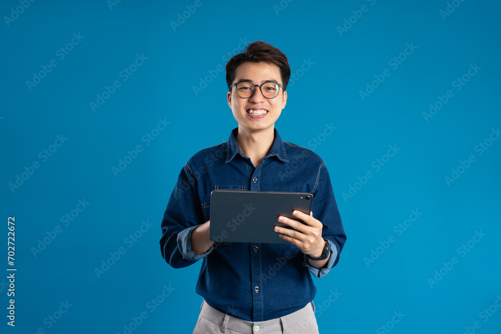Portrait of young Asian business man posing on blue background Portrait of young Asian business man posing on blue background