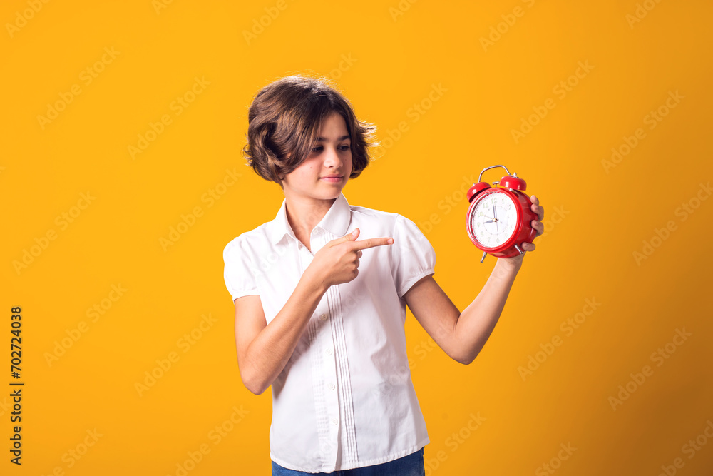 Child girl holds an alarm clock in hand and pointing at it. The concept of education, school, deadlines, time to study Child girl holds an alarm clock in hand and pointing at it. The concept of education, school, deadlines, time to study