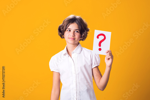 A portrain of kid girl holding question mark card. Children, idea and knowledge concept