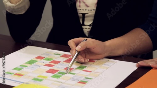 Steadicam Close up Shot of Two Women Discussing Project Timeline Actively With Pens Poking At A Printed Table