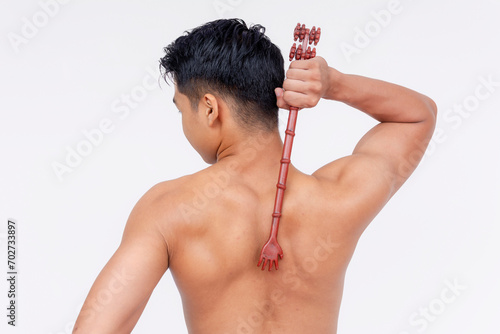 A topless asian man using a backscratcher to scratch a acnestis. Isolated on a white backdrop. photo