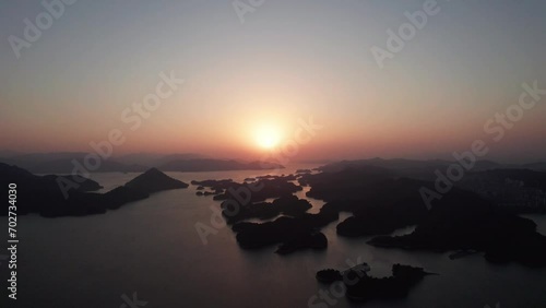 Aerial view of thousands of islands in Qiandaohu lake in Chunan, Hangzhou, Zhejiang, China. Beautiful sunset on lake, golden sun and silhouette islands, 4k real time footage, drone view. photo