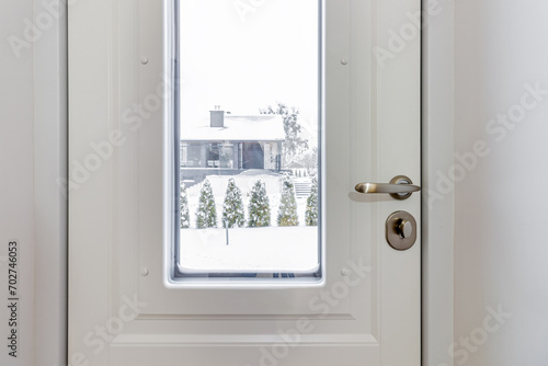 A fragment of a white door with glass, through which you can see a snow-covered courtyard