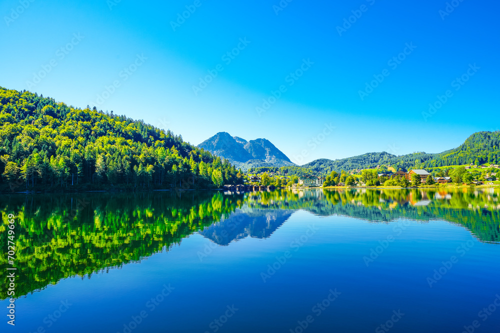 Naklejka premium Landscape at Lake Altaussee in the Salzkammergut in Austria. Idyllic nature by the lake in Styria. Altaussee at Totes Gebirge with a view of the surrounding mountains. 