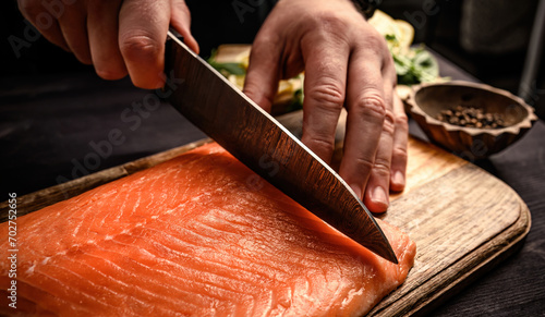 Sushi chef cuts raw salmon with knife photo