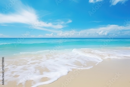 a sandy beach with a wave coming in to the shore and a blue sky with white clouds in the background. © Shanti