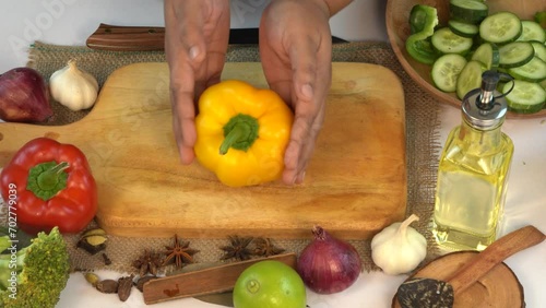 A female hands taking Yellow Bell Peppers on a Wooden Board
