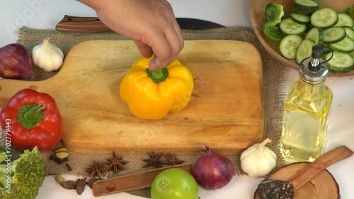 A female hands yellow bell pepper on wooden board