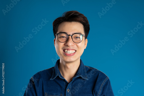 Portrait of young Asian business man posing on blue background photo
