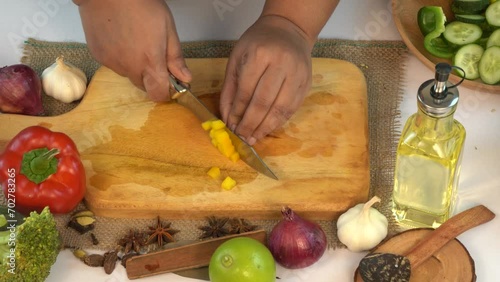 Female hands with a knife chop fresh garlic on a cutting wooden board