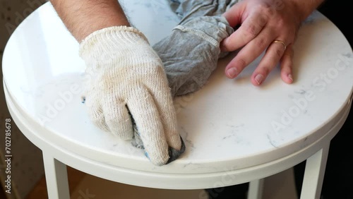 Person is wiping a surface of marbled round coffee table, selective focus. Process of making a handmade piece of furniture photo
