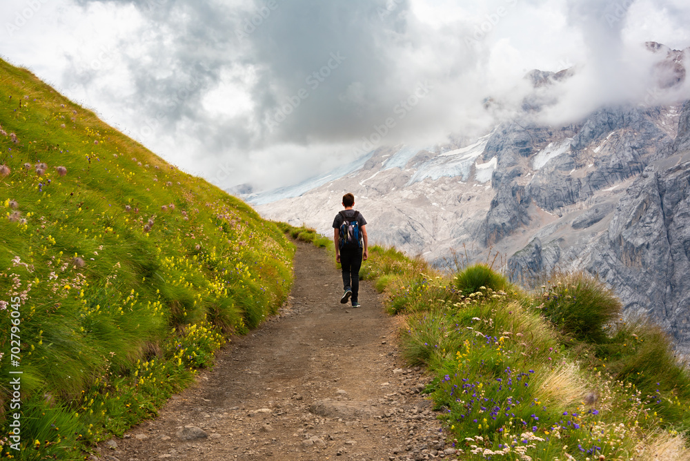 Hiker walking on trail in Dolomite alps, mountain in summer