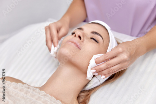 beautician cleanses skin of beautiful woman with sponge. Perfect cleaning, spa treatment skincare face.