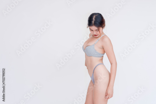 A confident southeast asian woman wearing only gray bra and panties and flaunting a slim sexy body. Isolated on a white backdrop.