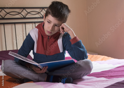 Bored schoolboy do task tired exhausted upset fatigued unmotivated little child boy kid pupil schoolchild on the bed bored, class lesson education learning problems school