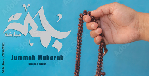 Jummah Mubarak blessed happy Friday Arabic calligraphy, Selective focus image hand of Muslim woman holding prayer beads. photo