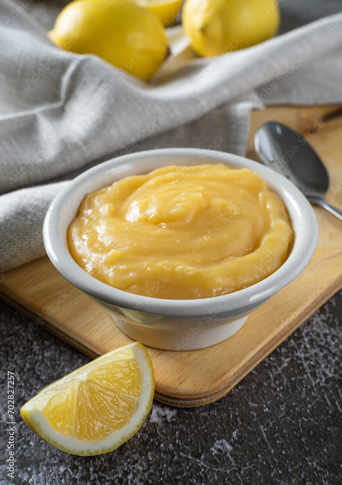 Homemade lemon curd or cream in bowl, with fresh lemons on a gray background. Homemade lemon curd or cream in bowl, with fresh lemons on a gray background.