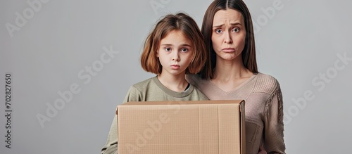 Mother and daughter moving to a new home holding cardboard box skeptic and nervous frowning upset because of problem negative person. with copy space image. Place for adding text or design photo